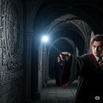 Wizard casting Lumos in a dark Hogwarts corridor with glowing wand tip. practicing wizarding spells